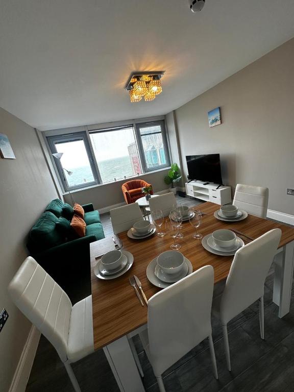 a living room with a dining room table with white chairs at Stunning Sea View 2BR Flat Sleeps 5 Walk to Beach - Big Savings for Extended Stays - by Nestora Stays Ltd in Brighton & Hove