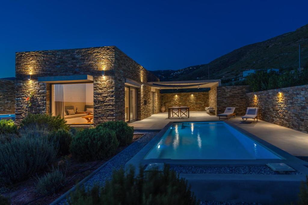 a villa with a swimming pool at night at Gray and Blue in Andros