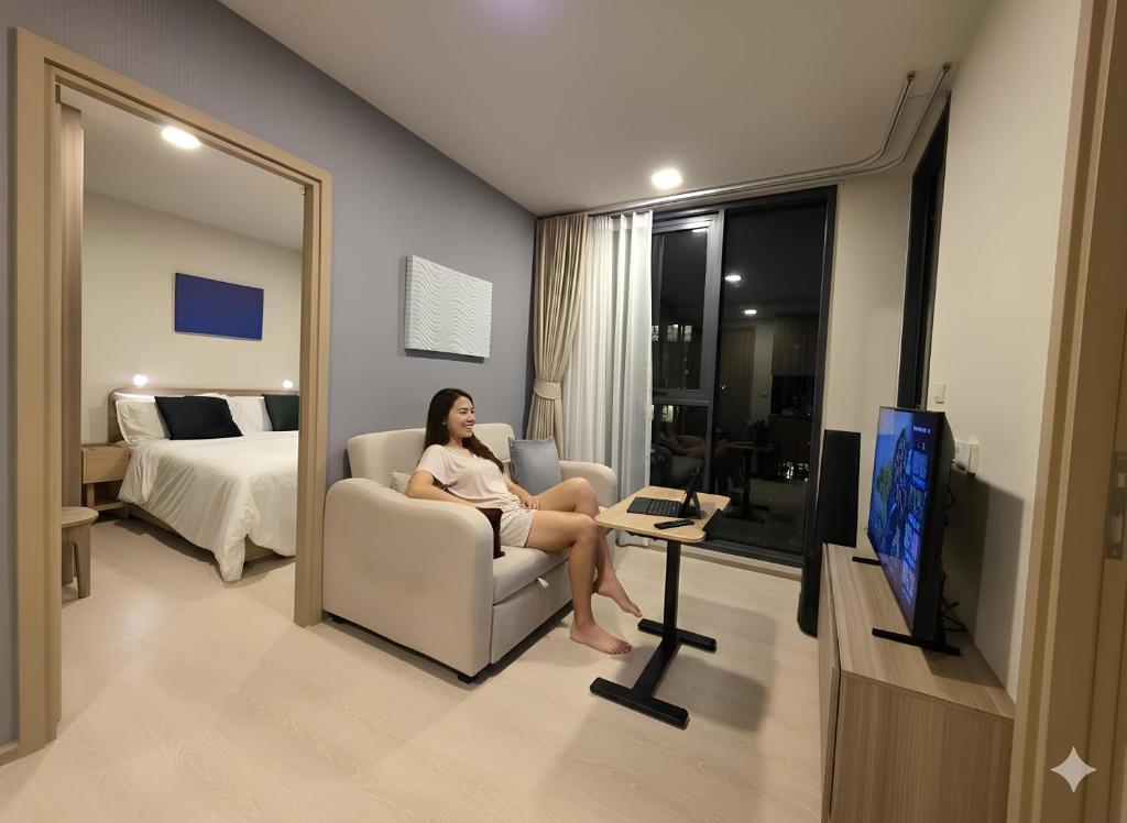a woman sitting in a chair in a hotel room at The Rock Condo Central Phuket "Min-1 week" in Ban Rangeng