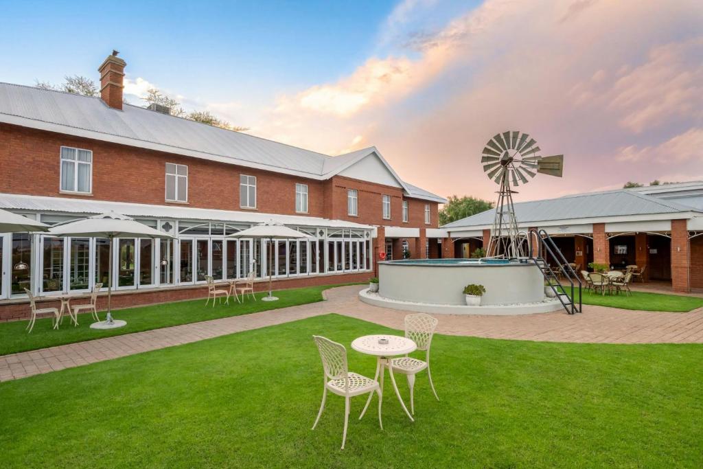 a building with a windmill and a table and chairs at Protea Hotel by Marriott Kimberley in Kimberley