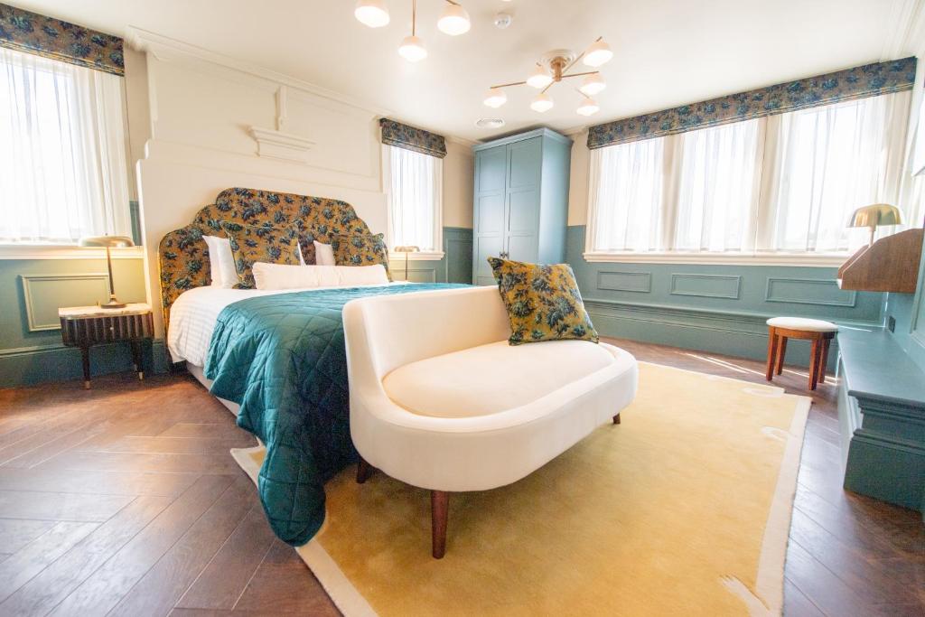 a bedroom with a bed and a chair and windows at The Carre Arms Hotel & Restaurant in Sleaford