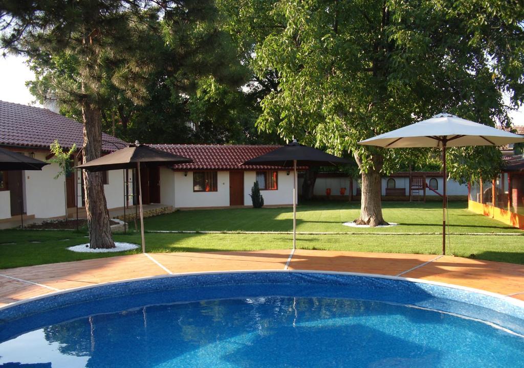 a swimming pool with two umbrellas and a house at Bolyarski Stan Guest House in Veliki Preslav