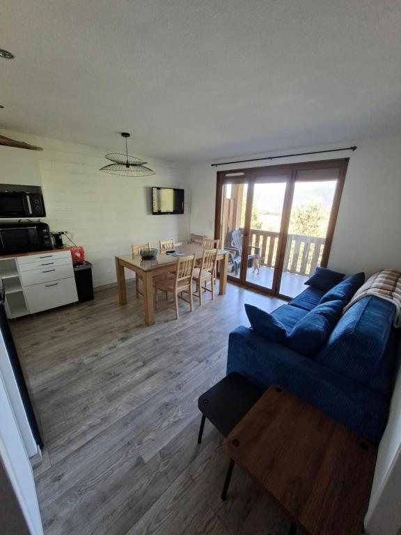 a living room with a blue couch and a table at Entre lac et montagne in Les Angles