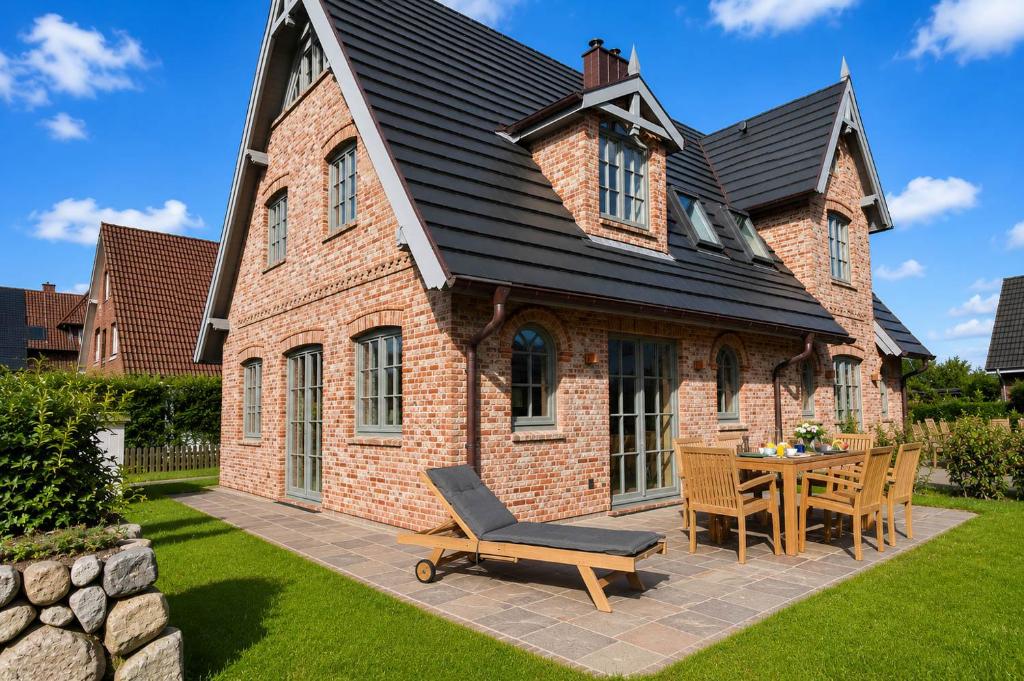 a house with a patio with a table and chairs at Die Perle von Wenningstedt in Braderup