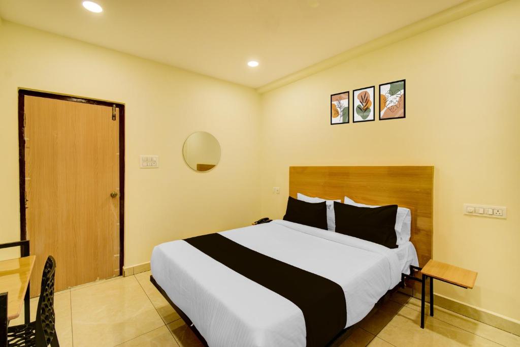 a bedroom with a bed and a table and a door at Super Hotel O Nivara in Hyderabad