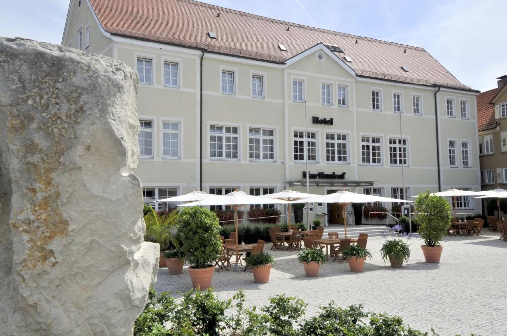 a large building with tables and umbrellas in a courtyard at Martinshof in Rottenburg