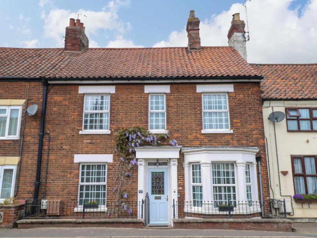 a red brick house with a white door at Springfield in Fakenham