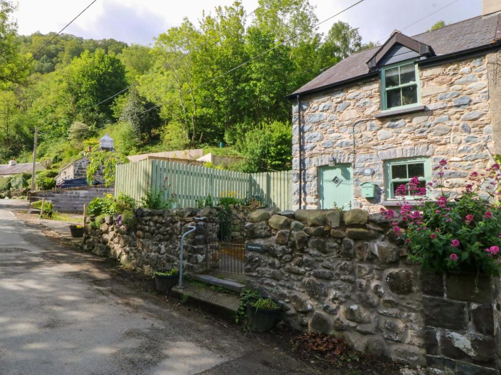 a stone house with a stone fence and flowers at Old Chapel House in Llanfairfechan