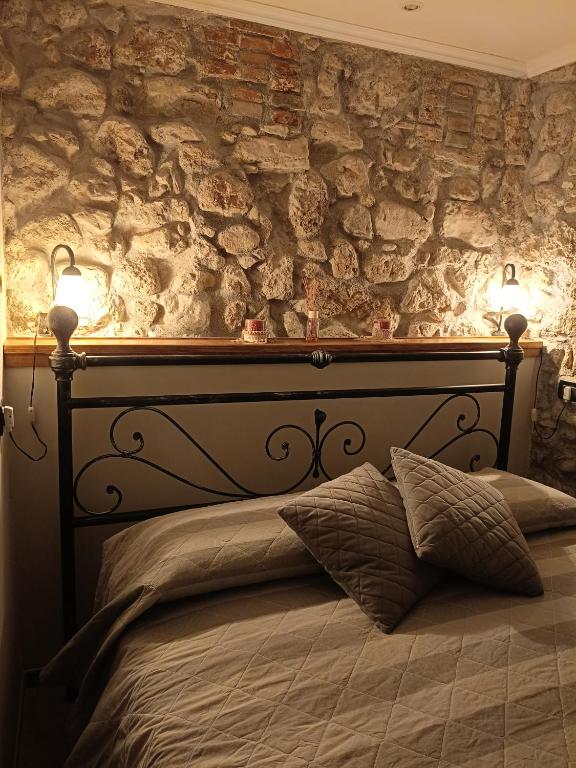 a bed with two lights on a stone wall at La Tavernetta in Casto