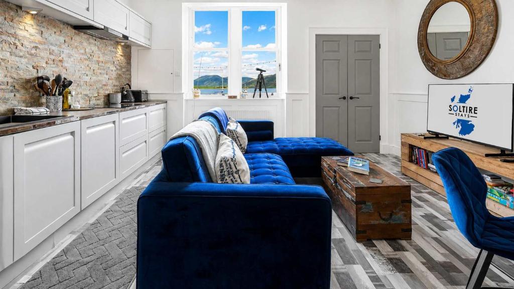 a living room with blue couches and a kitchen at Melbourne Place Apartment in Port Bannatyne