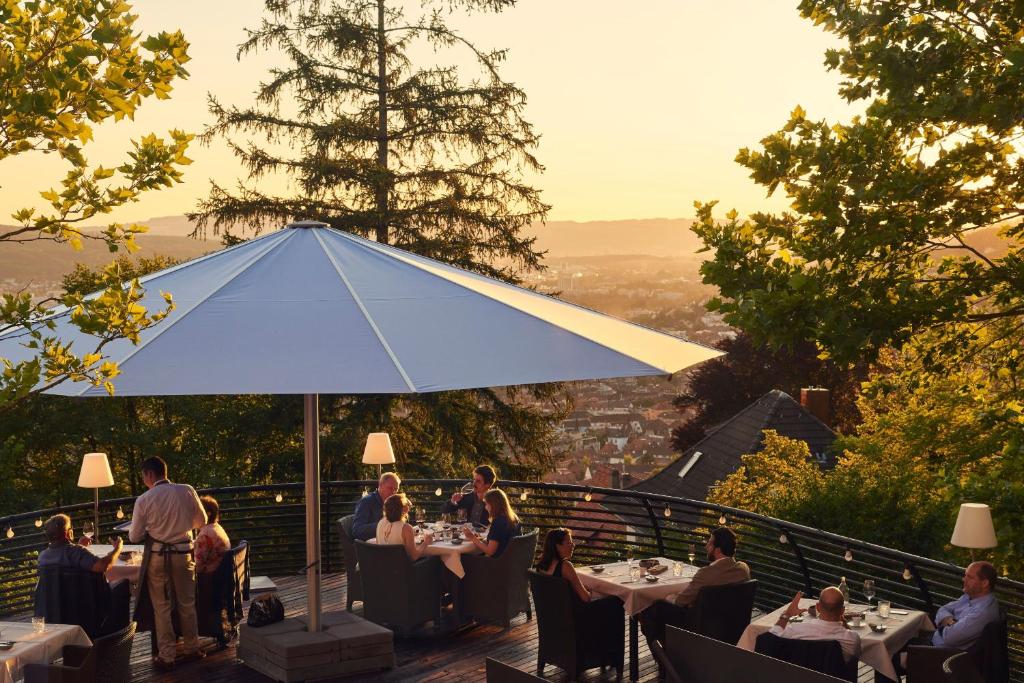 a group of people sitting at tables under a blue umbrella at Studios & Spa Suites Rigiblick in Zurich