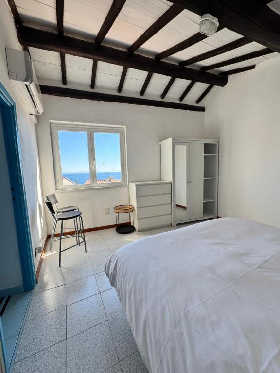 ein Schlafzimmer mit einem Bett, einem Stuhl und einem Fenster in der Unterkunft Bocca D'oro S1 in Isola del Giglio