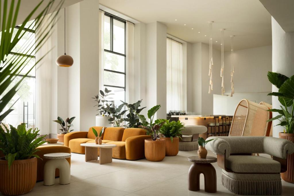 a living room with orange furniture and plants at Sandbourne Santa Monica, Autograph Collection in Los Angeles