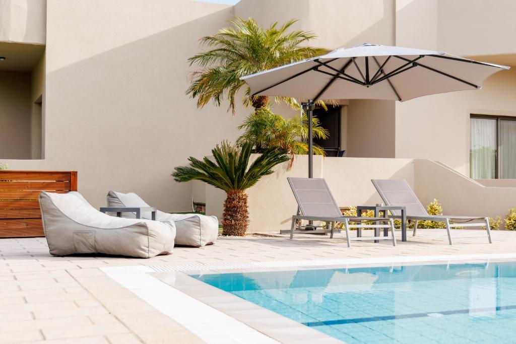 a swimming pool with chairs and an umbrella at Villa Katrin in Ialysos