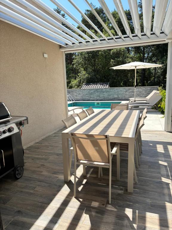 a patio with a table and chairs and a grill at villa des gorges in Vagnas