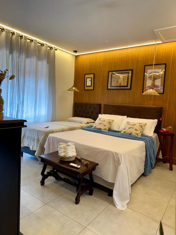 a hotel room with two beds and a table at EcoStay Lençóis - apartamento in Lençóis