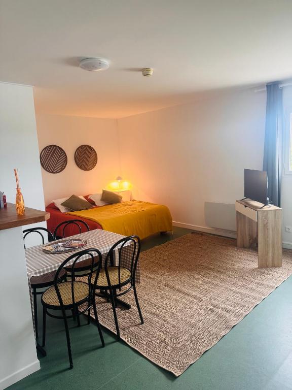 a bedroom with a bed and a table and chairs at Studio les Écuries de la forêt 2 in Le Buisson Genois