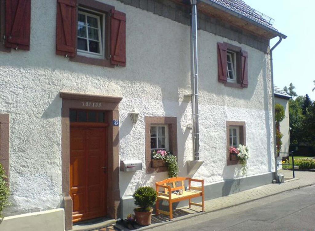 ein weißes Haus mit einer Holztür und einer Bank in der Unterkunft Relaxen am Nationalpark Eifel in Ahrhütte