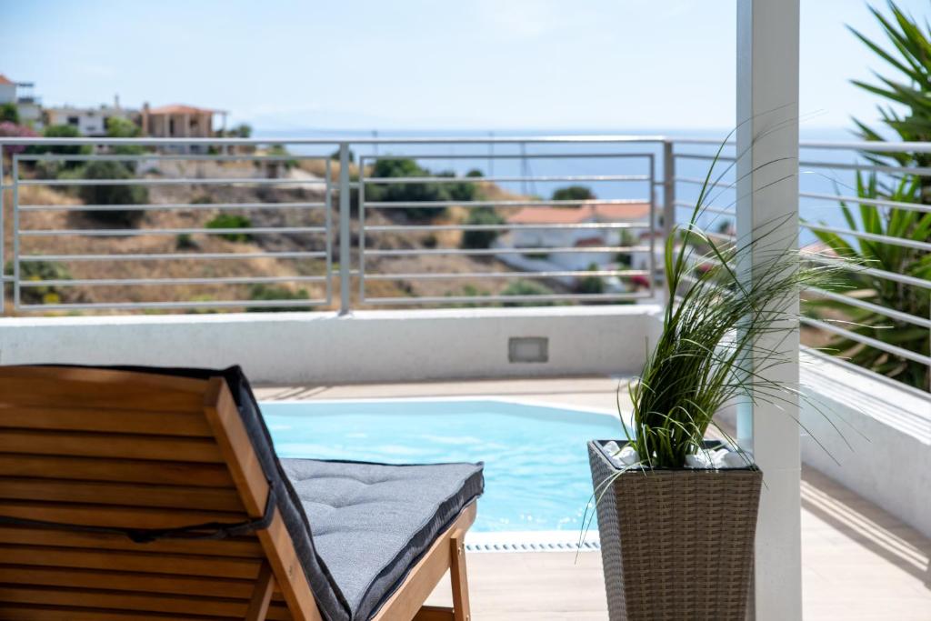 a balcony with a chair and a swimming pool at Oasis Resort Pure Relaxation Serenity in Agia Marina Mikrolimanou