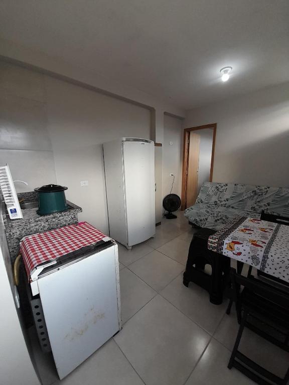 a small kitchen with a refrigerator and a table at Kitnet Perequê in Matinhos
