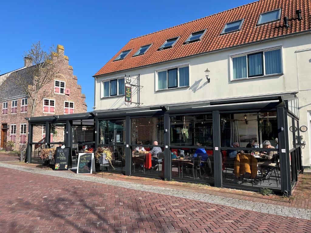 a building with a restaurant with people sitting at tables at Hotel Café Restaurant "De Kroon", inclusief ontbijt in Wissenkerke