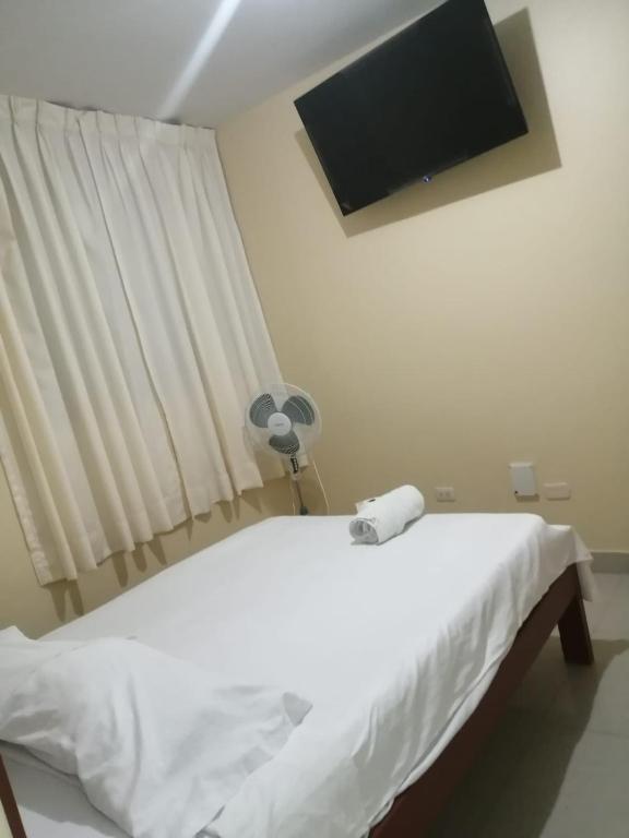 a bedroom with a white bed with a fan at Hospedaje San Valentin in Capitan Concha