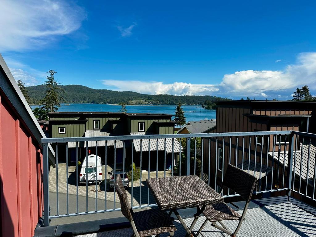 a balcony with two chairs and a table and a lake at Sooke Harbour Townhouse - Waterfront 2-Bed Rental in Sooke
