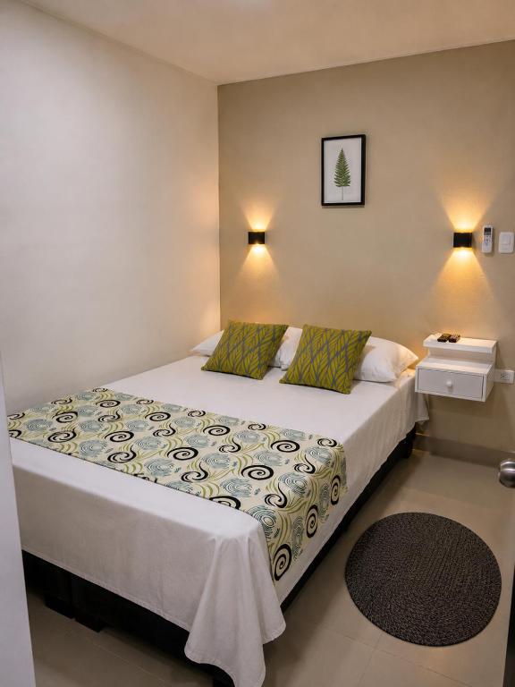 a bedroom with a bed with a white bedspread at Hostal Caiman Del Rio in Barranquilla