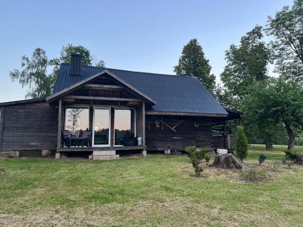 a log cabin with a large window in a yard at Pas Šerną in Macionys