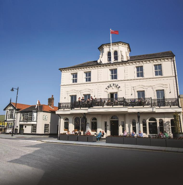 a white building with people sitting on a balcony at The Pier Hotel in Harwich