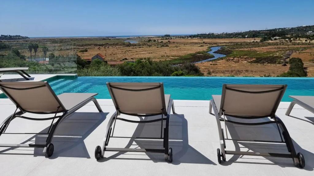 two chairs and a table on a patio with a pool at Villa Aurora Luxury Villa with Infinity Pool in Portimão