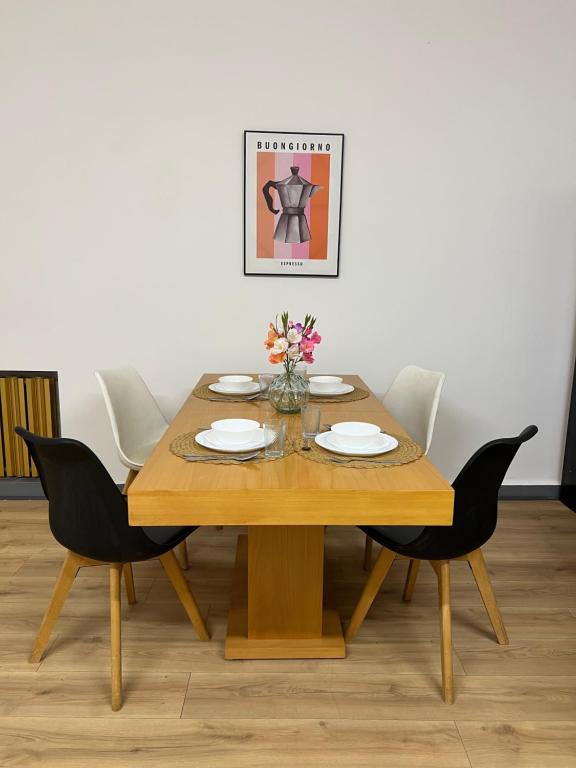 a wooden table with plates and flowers on it at Apartament przy Agorze in Bytom