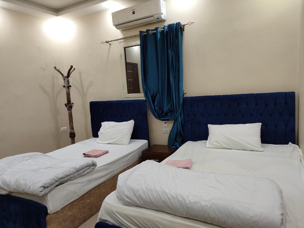 two beds in a room with blue curtains at Egyptian guest house in Cairo