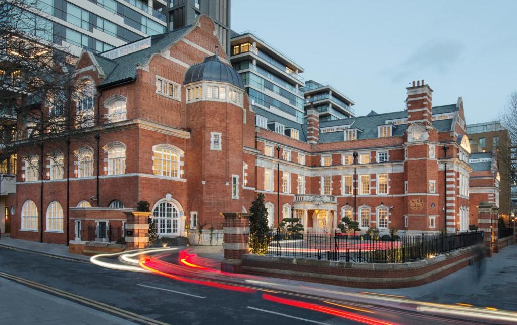 un grande edificio in mattoni rossi con traffico di fronte di The LaLit London - Small Luxury Hotel of the World a Londra