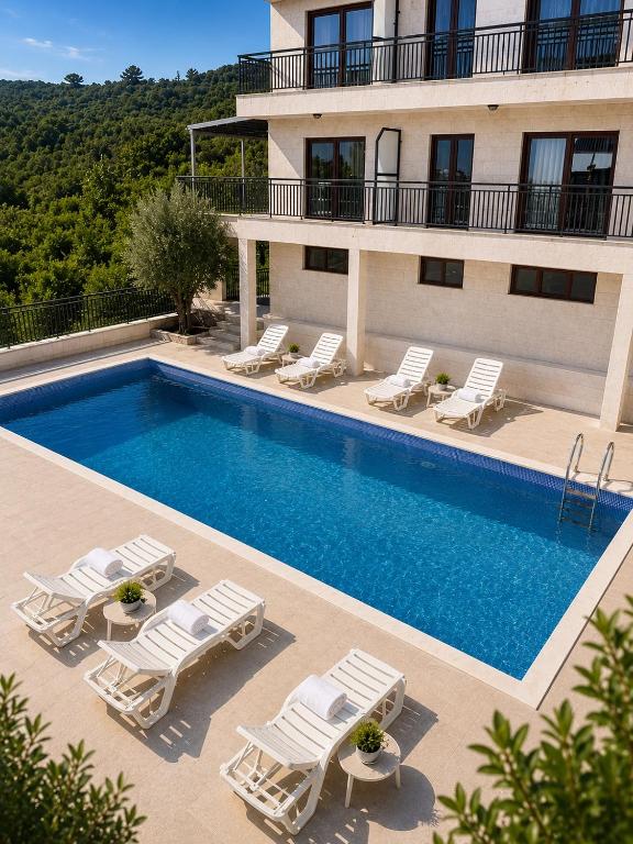 a swimming pool with lounge chairs and a building at Lavander Apartment W Pool and Private Beach in Tivat
