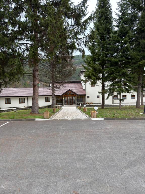 a large white building with trees and a driveway at Konak Studenica 1186 in Kraljevo
