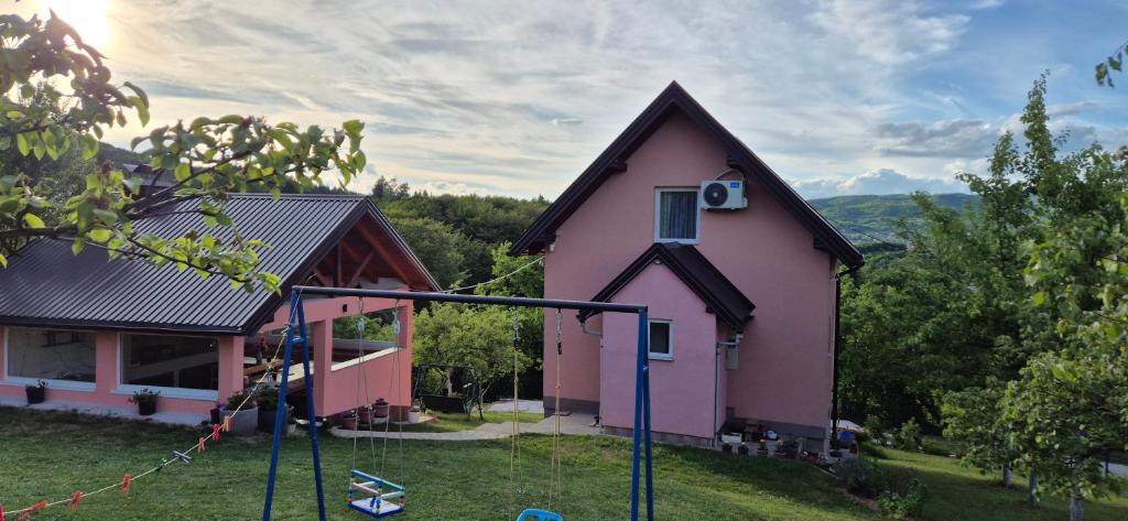 a pink house with a playground in front of it at Villa Miševići in Hadžići
