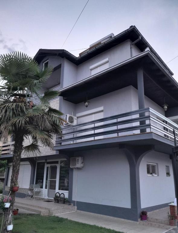 a white house with a palm tree in front of it at Apartman ZAFIROVI in Gevgelija