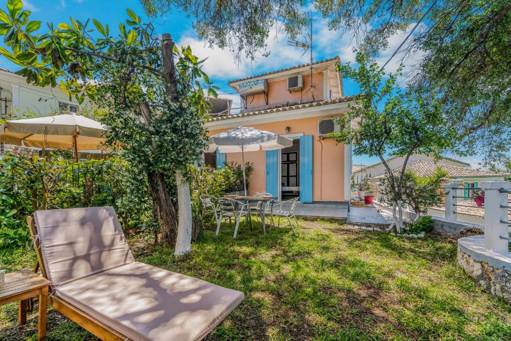 a garden with a table and chairs in front of a house at Aiolos Rooms in Tsoukalades