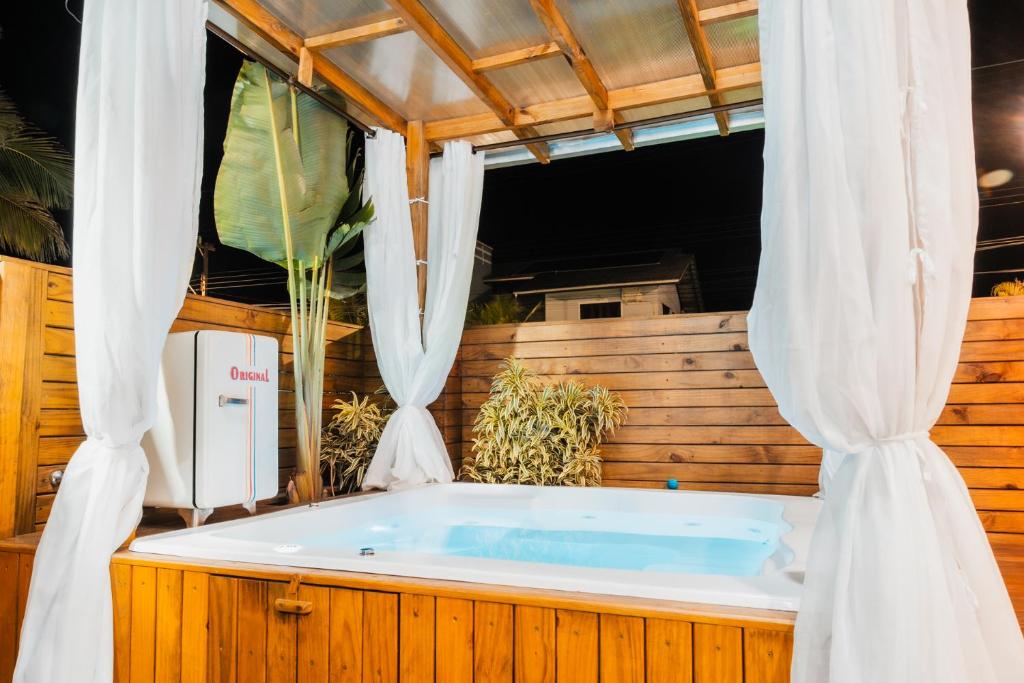 a jacuzzi tub in a room with curtains at The Beach House Estadias in Itapoa