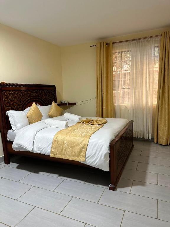 a bedroom with a large bed with white and gold sheets at Entebbe Gardens Resort in Kitengela 