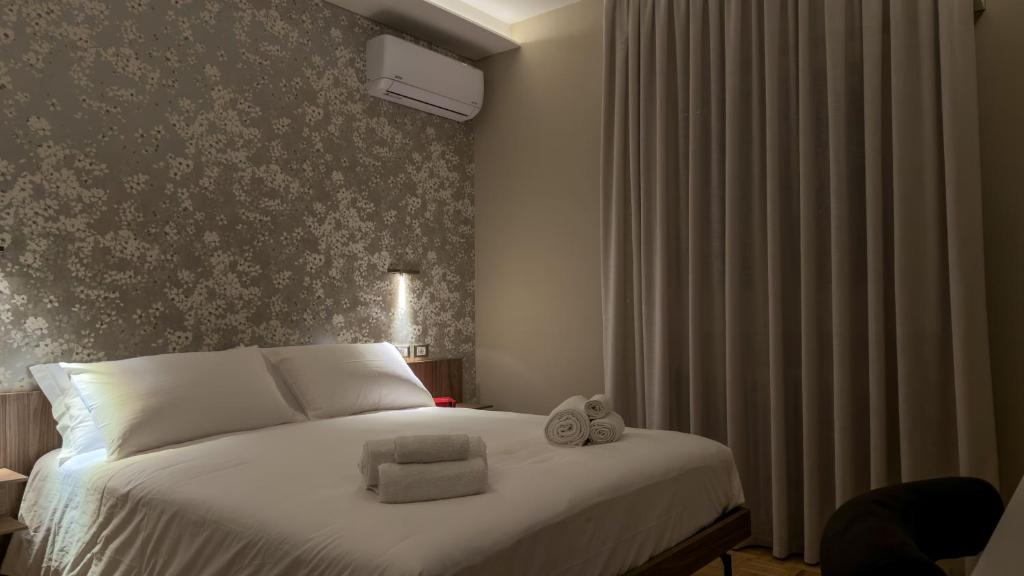 a bedroom with a bed with white sheets and a wall at L'Alòz in Lugo