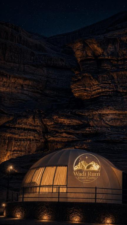 a building in front of a rock wall at night at Wadi Rum Dome Camp in Disah