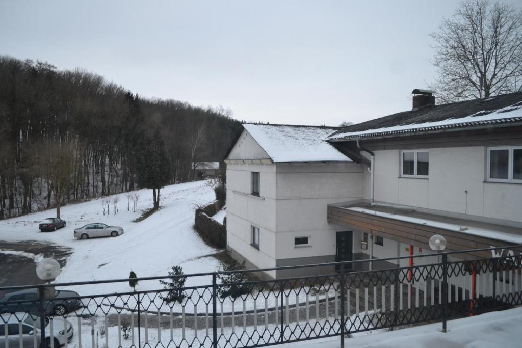 a house with snow on the ground next to a car at Pension Waldesruh in Linz