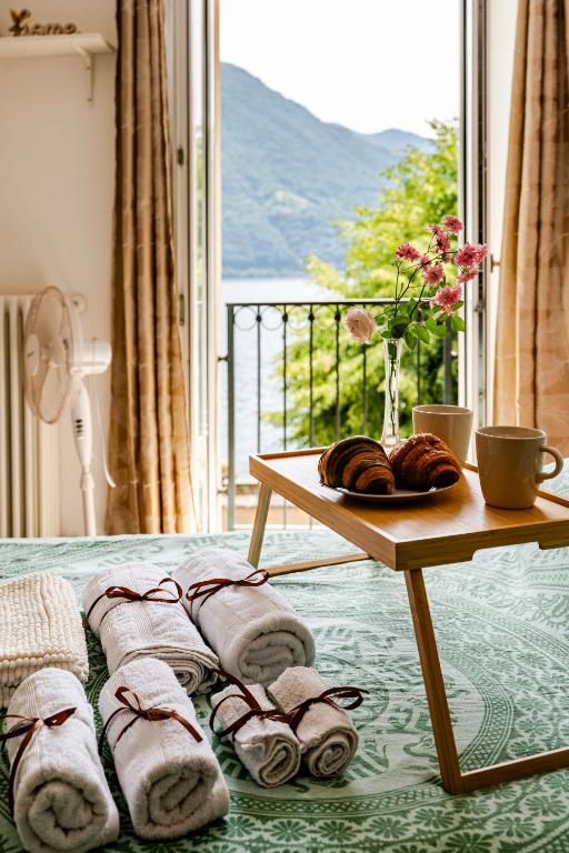 a table with towels on a bed next to a window at Lakeside Paradise Porlezza in Cima