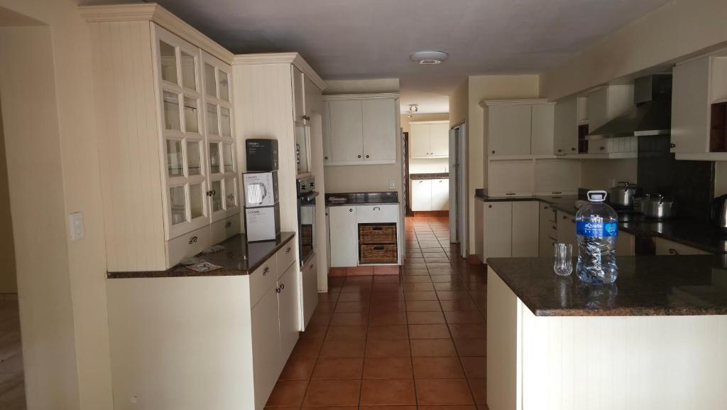 a kitchen with white cabinets and a bottle of water on the counter at 3D Power guest house in Durban