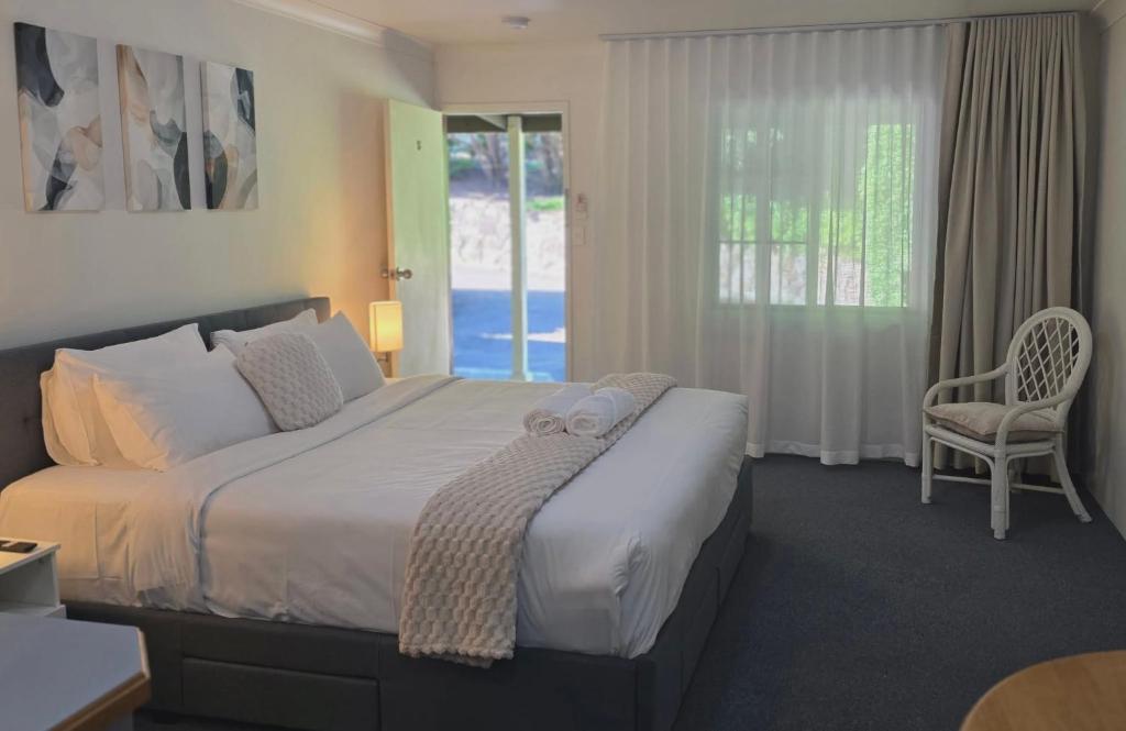 a bedroom with a bed and a chair and a window at Flaxton Country Lodge in Flaxton