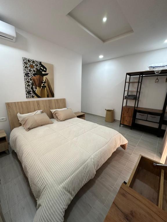 a bedroom with a large bed and a painting on the wall at Appart Yassou in Dar Salah Bey