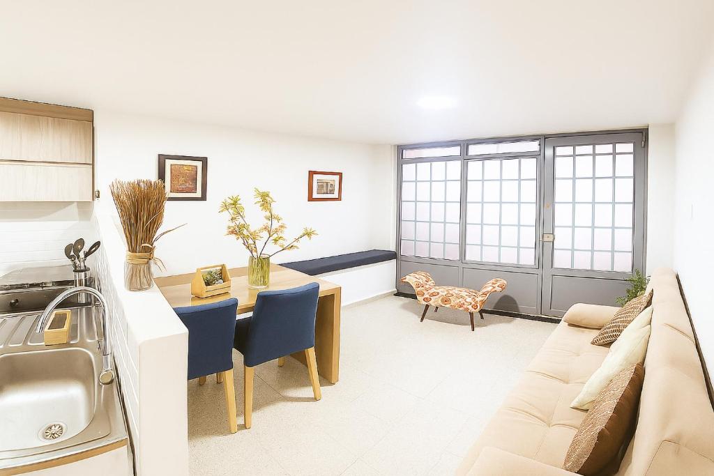 a kitchen and living room with a couch and a table at Loft cerca a Laureles, WIFI, cerca metro, con Balcón, GUARDA MALETAS GRATIS!! in Medellín