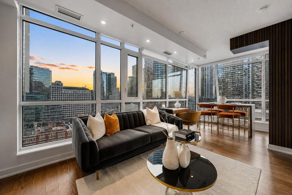 a living room with a couch and large windows at NoMad Suites - Toronto's Entertainment District in Toronto